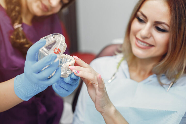 Dentista explica sobre coroa depois do tratamento de canal usando modelo odontológico com paciente na GEN Odontologia em Higienópolis.