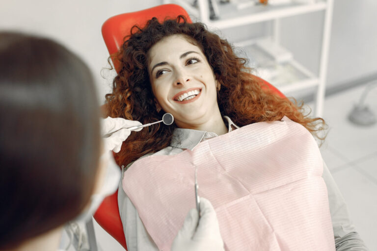 Mulher sorridente na cadeira do dentista pós-tratamento de canal em Higienópolis. Cuidados essenciais na Clínica GEN Odontologia.