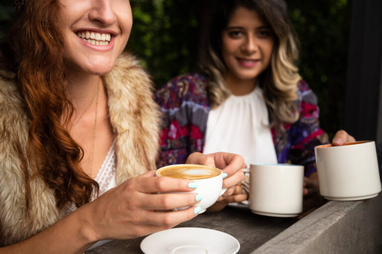 Mulher sorrindo segura xícara de café, ilustrando cuidados ao tomar bebidas com alinhadores Invisalign na Odonto GEN em Higienópolis.
